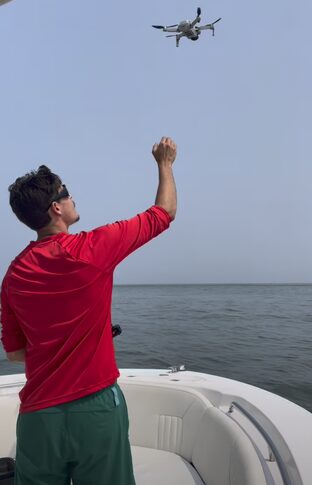 Jeremy hand-launching a drone from a boat at sea
