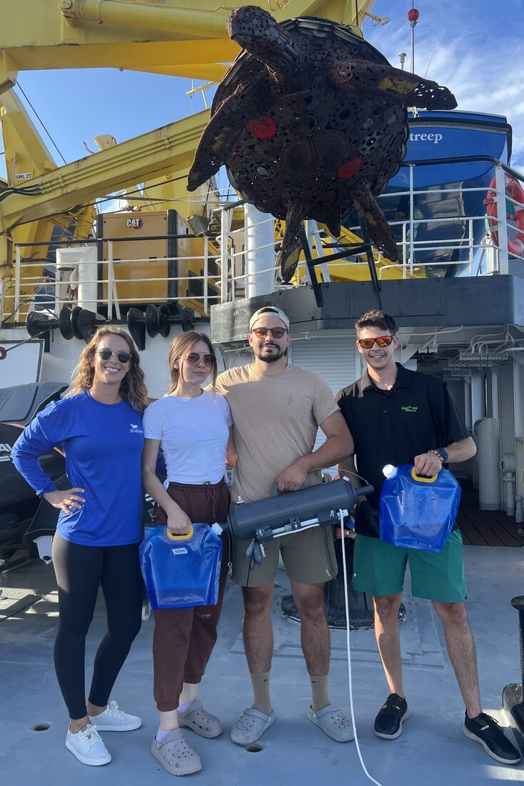 Research team on a ship deck holding eDNA sampling kits