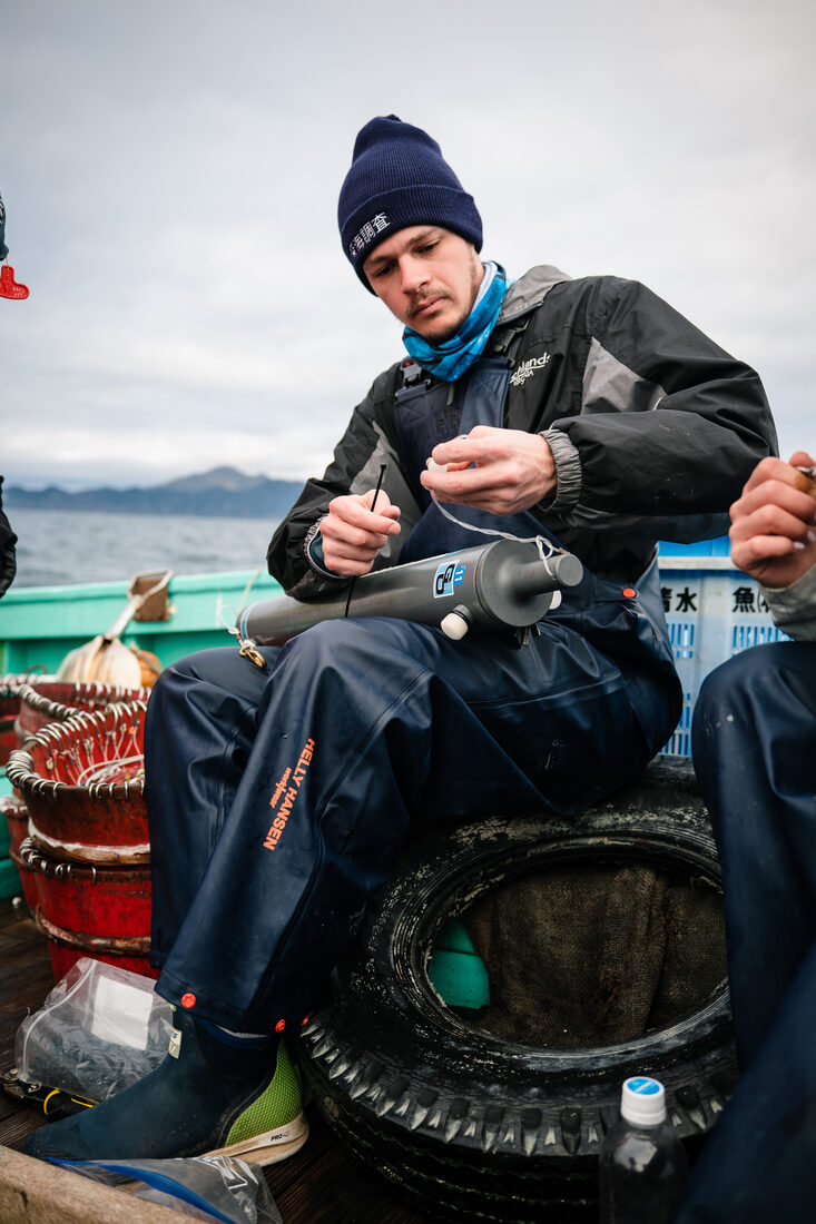 Jeremy sitting on a fishing vessel in Japan preparing gear
